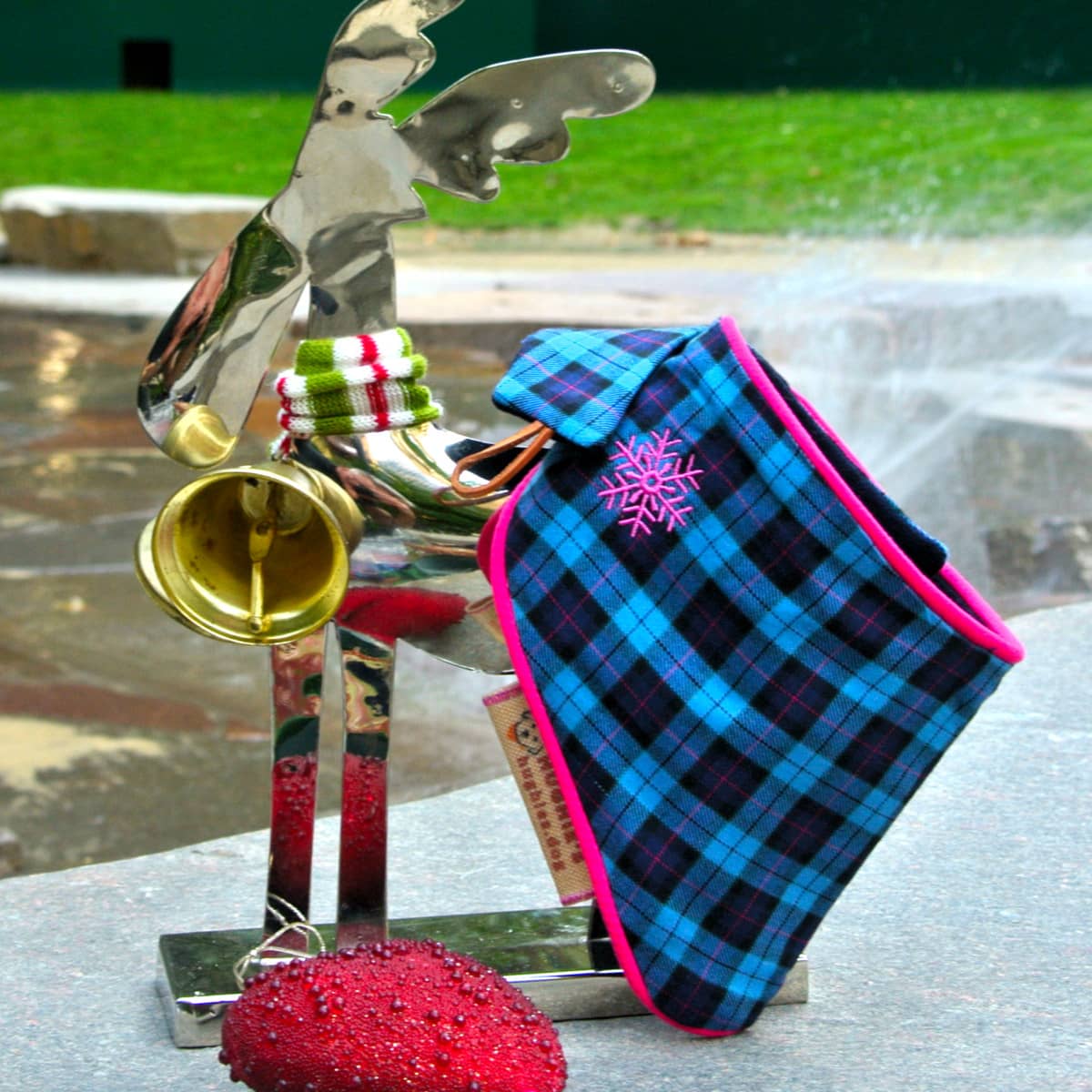 christmas tartan bandana with a silver reindeer ornament sitting on some stone