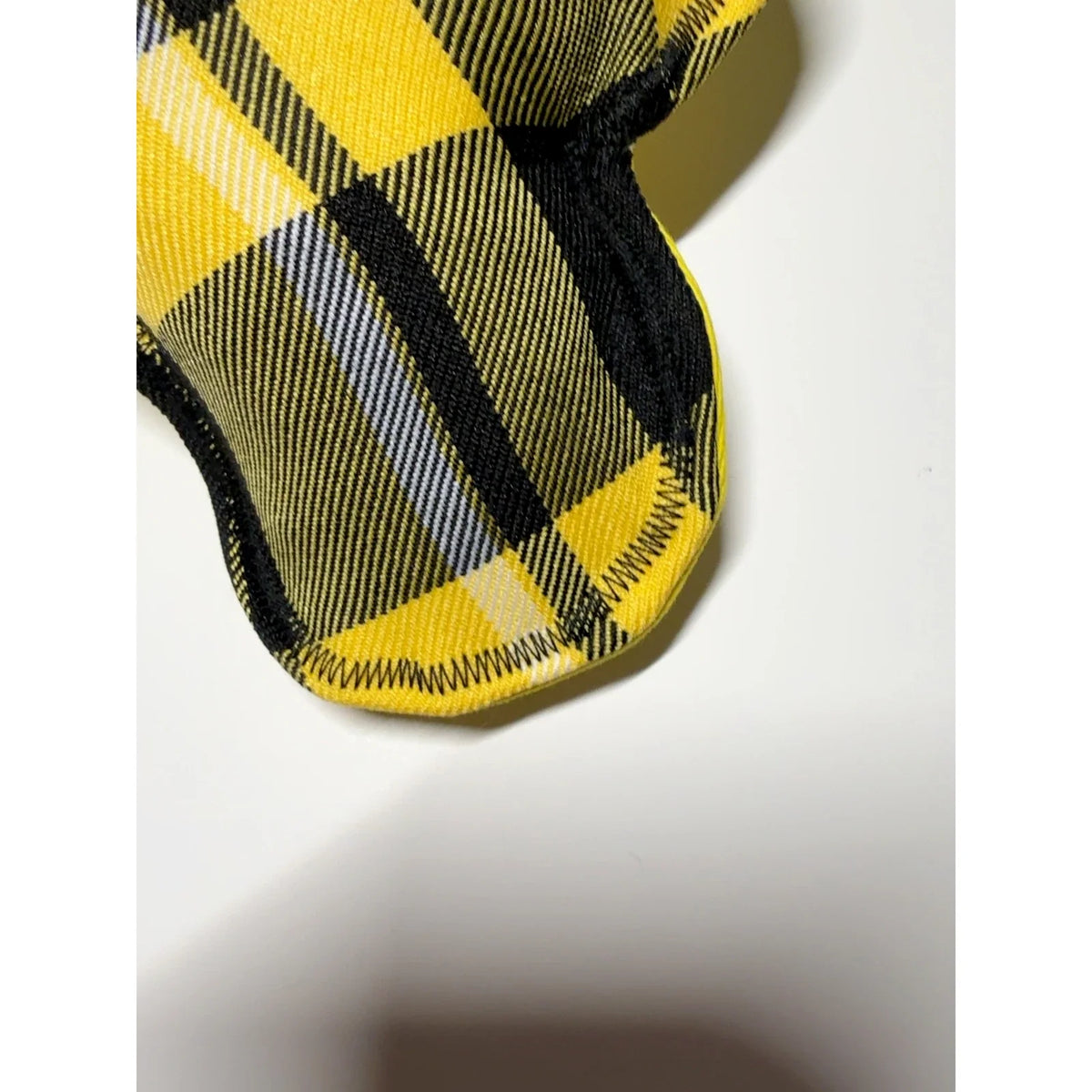 Close-up of yellow and black tartan dog bone toy fabric and zigzag stitching